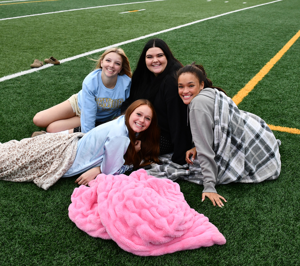 Four seniors laying on a football field. 