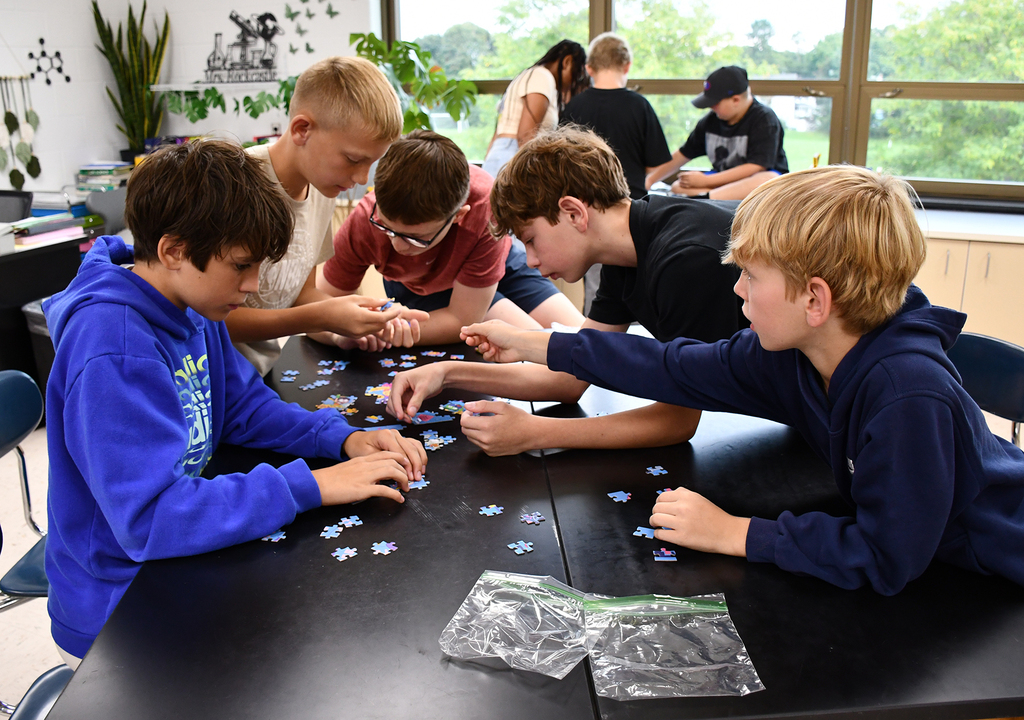 A group of 7th grade boys assembling a puzzle. 