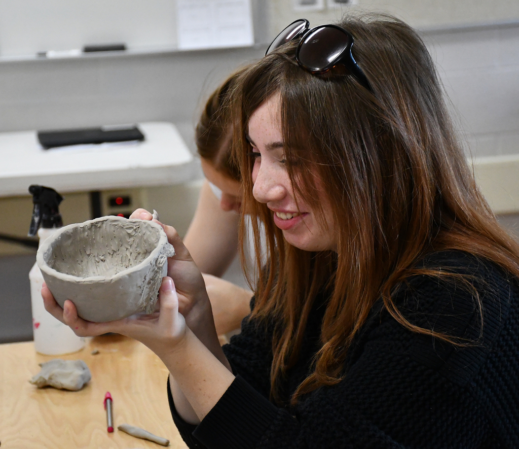 A high school girl working on a clay project. 