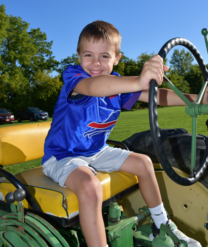 An elementary student sitting on a tractor. 