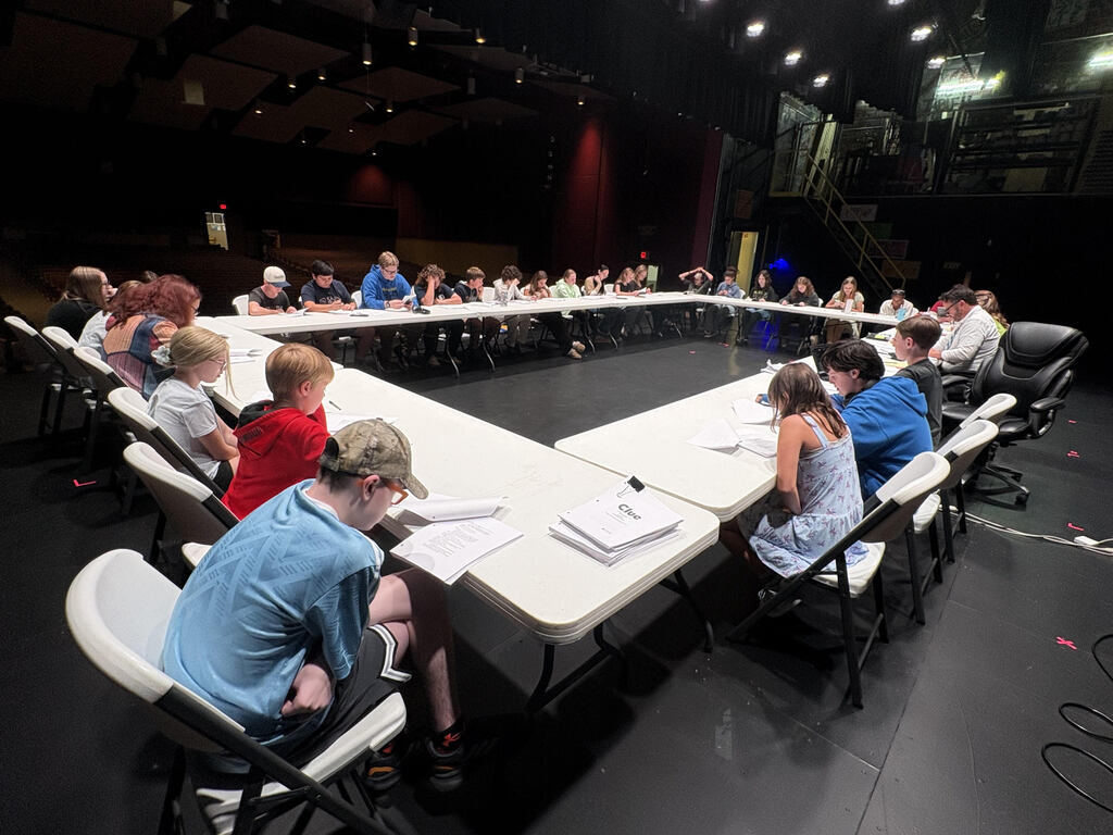 A cast and crew sitting on a stage.