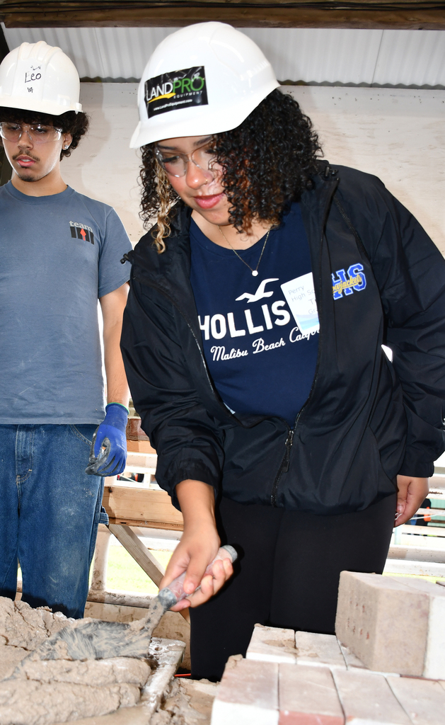 A girl trying to work with brick mortar. 