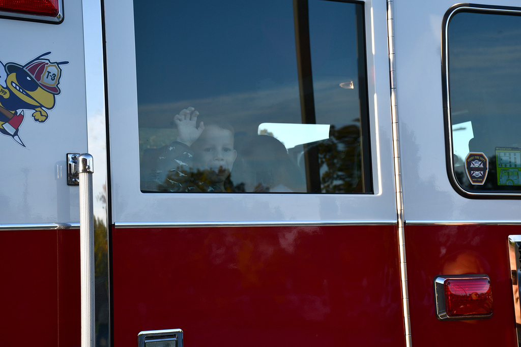 A little boy looking out the window of a fire truck. 