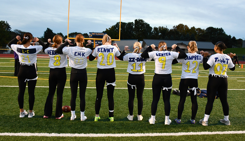 A group of students pointing to their jerseys. 