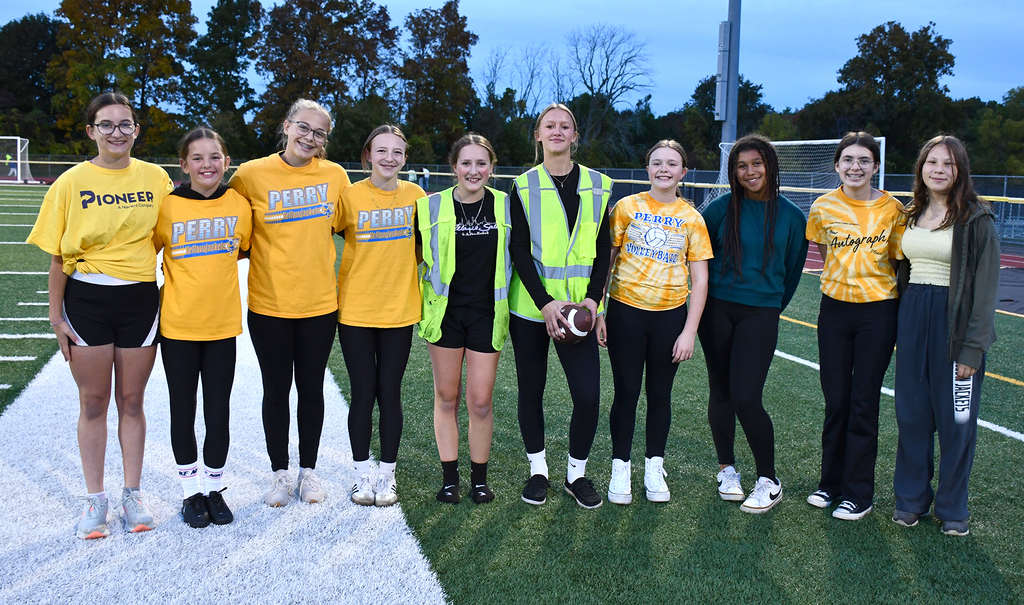 A group of students posing for a photo on a football field. 