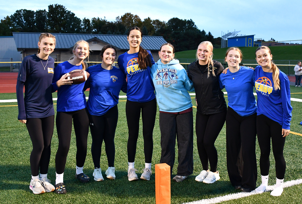 A group of students posing for a photo on a football field. 