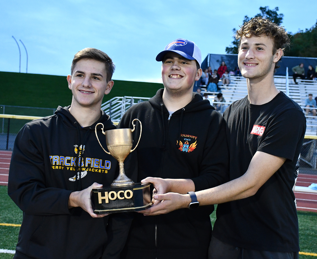 Three boys holding a trophy. 