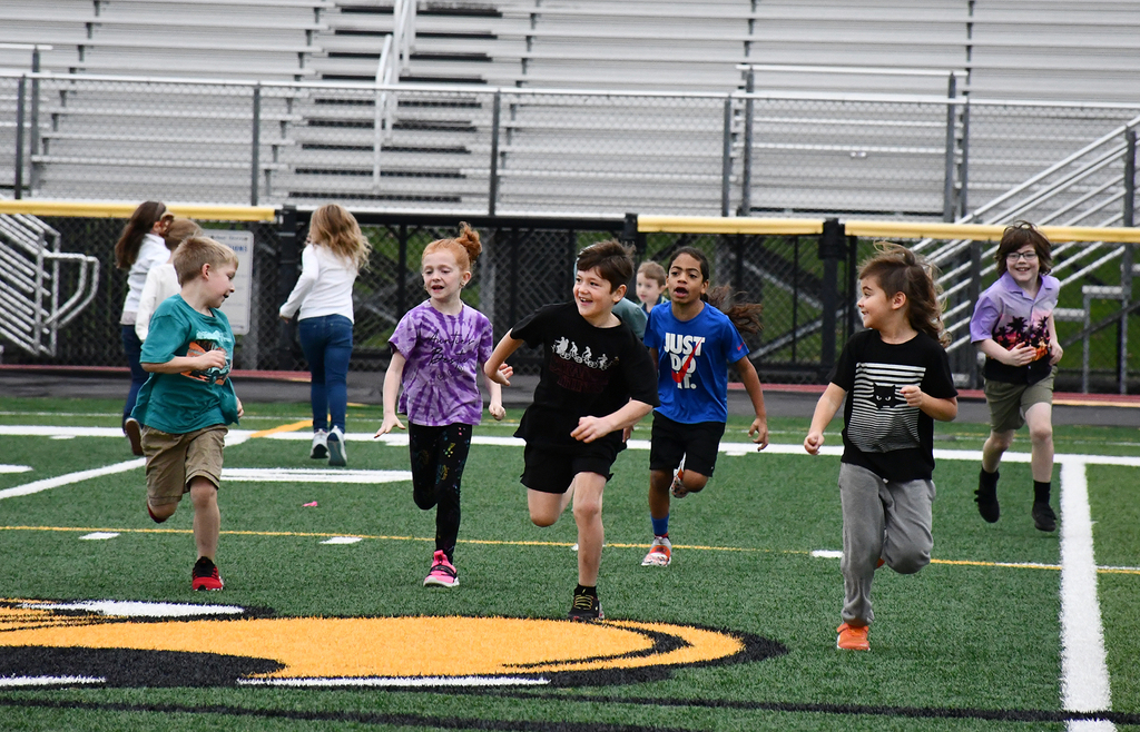 A group of students running on a turf field. 