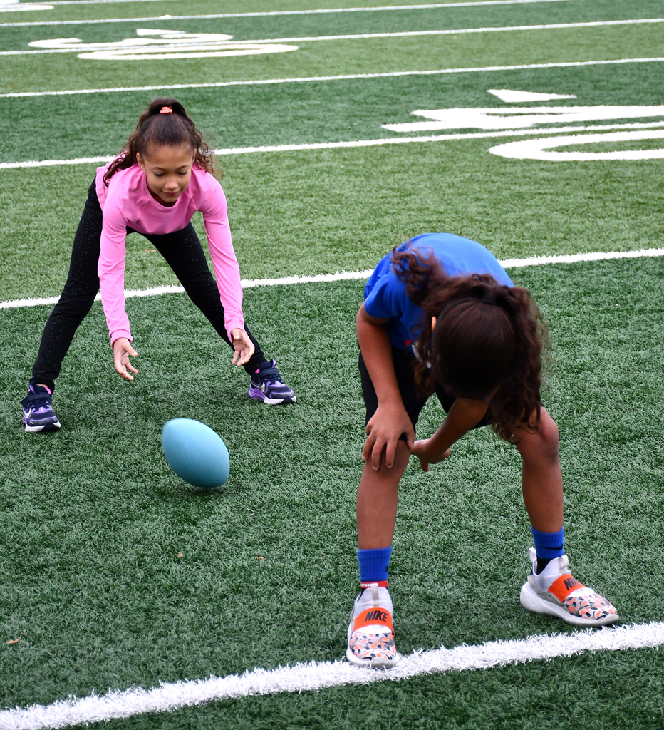 Two students learning to play football on a football field. 