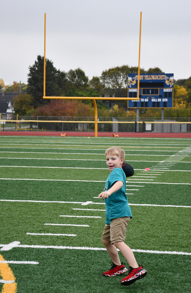 A boy throwing a football on a turf field. 