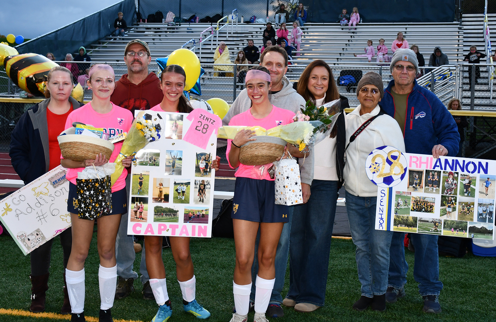 A group of people standing on a soccer field. 