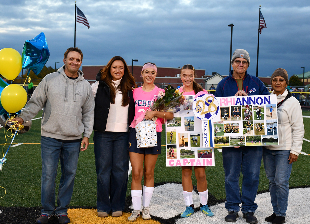 Six people standing together on a soccer field. 