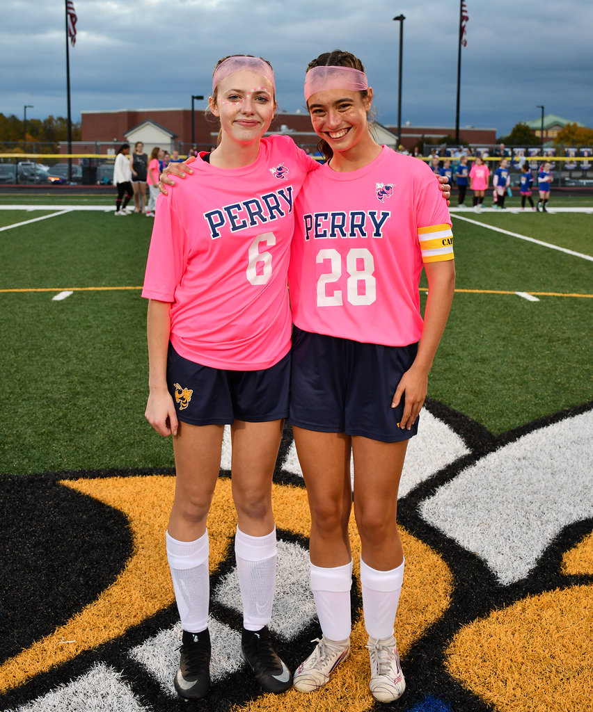 Two seniors standing together on a soccer field. 