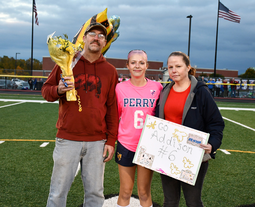 Three people standing together on a soccer field. 