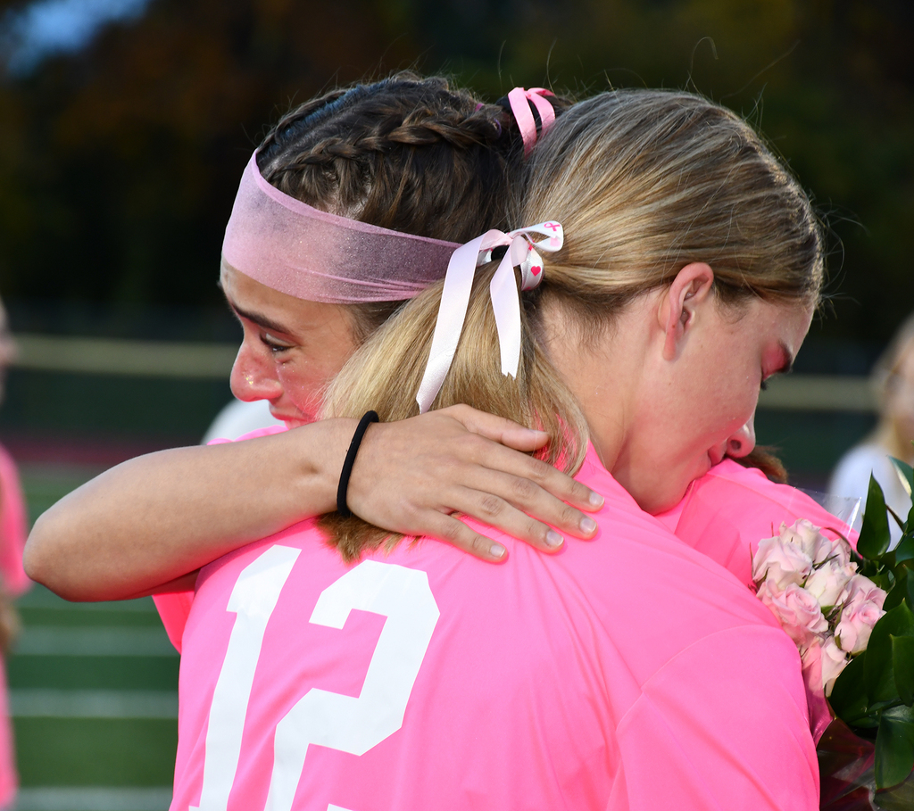 Two soccer players hugging each other. One is crying. 