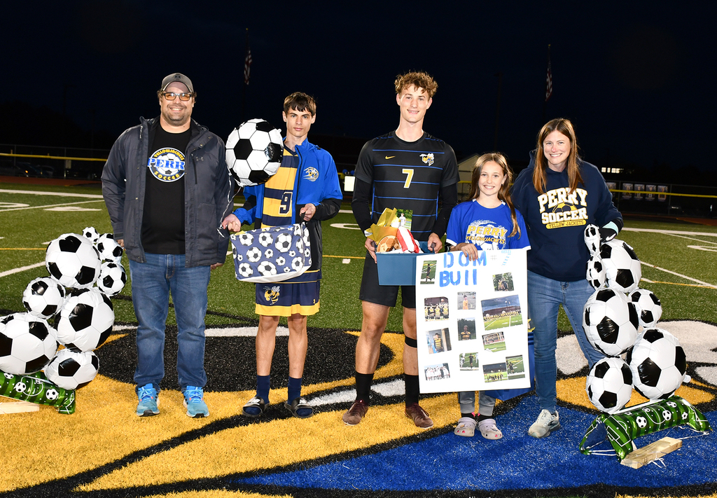 Five people standing on a soccer field. 