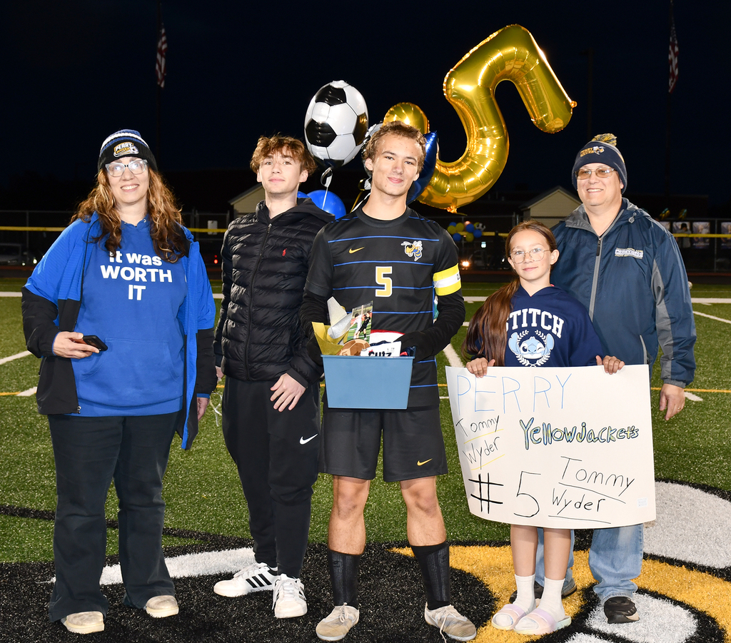 Five people standing on a soccer field. 