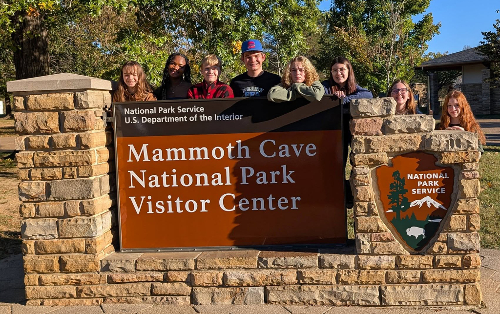 A group of students posing by a sign that says Mammoth Cave National Park Visitor Center.