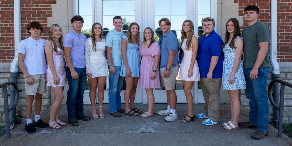12 members of the 2026 Homecoming Court stand in front of Old Senior High.
