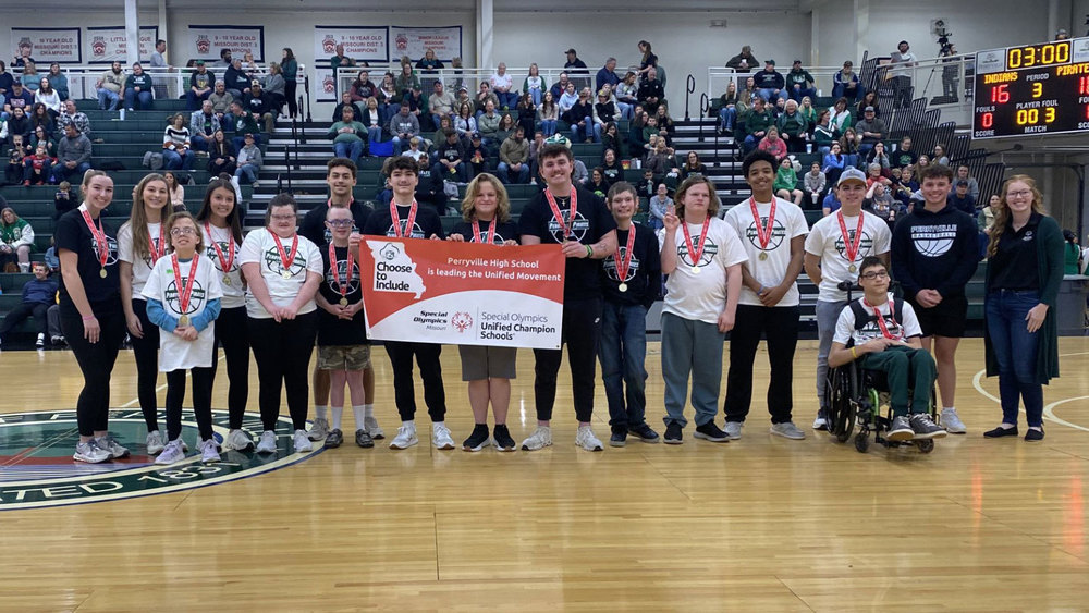 PHS  students pose on a basketball court holding a Special Olympics Unified Champion School banner.