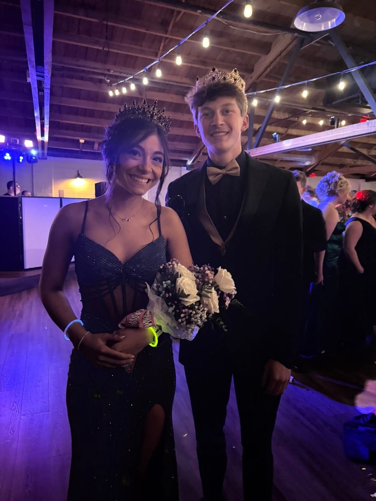 An image of Eloise Bollinger on the left and Aiden Wendel on the right. Both are wearing formal prom attire and wearing their prom Queen and King crowns. Eloise is also holding a bouquet of flowers.