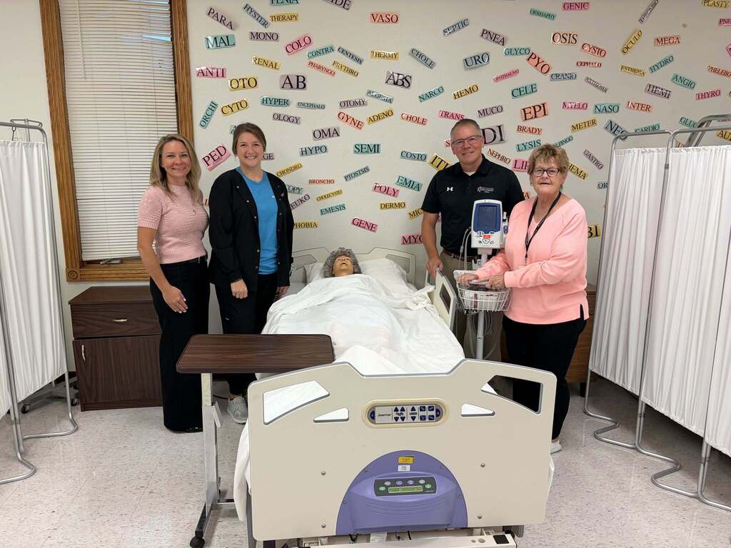Individuals stand alongside a bariatric bed that was donated to the Career Center by Mercy Hospital Perry.