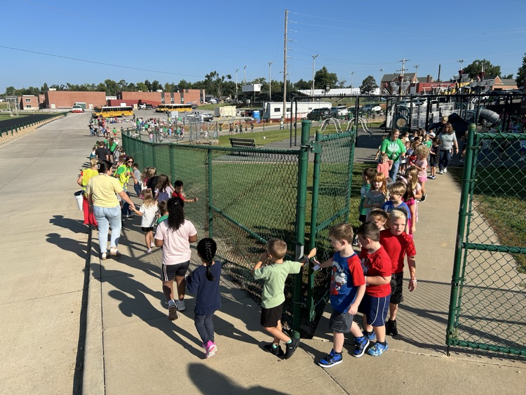 A line of children walking down a sidewalk.