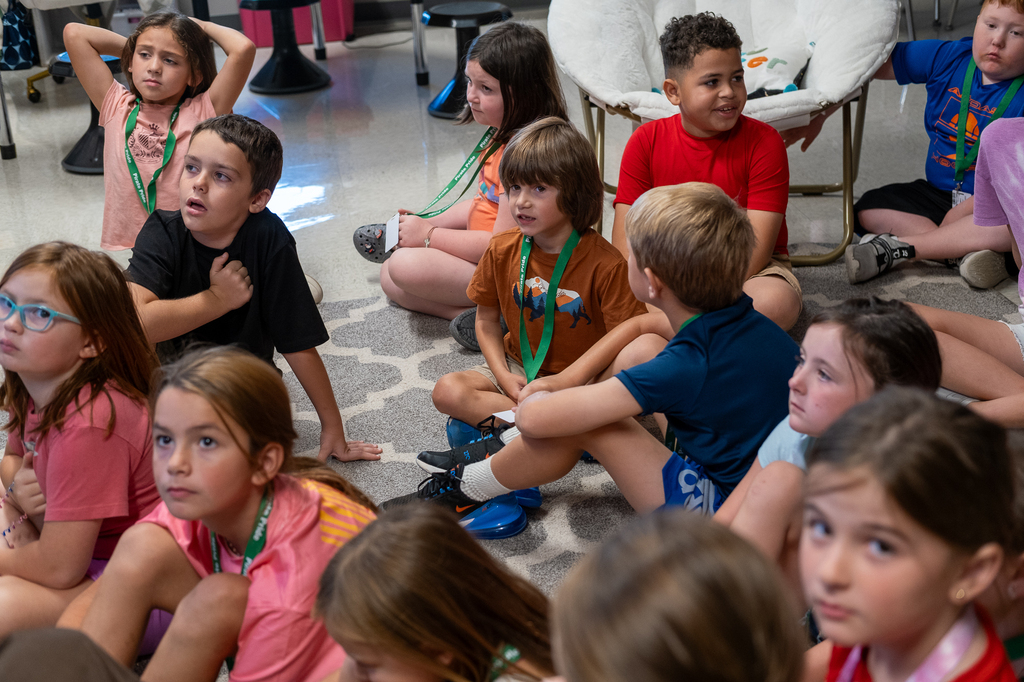 A student speaks amidst a seated crowd of classmates.