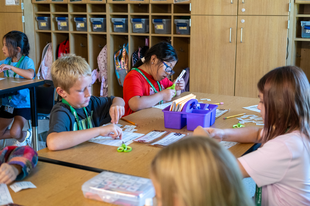 Students cut paper with scissors.