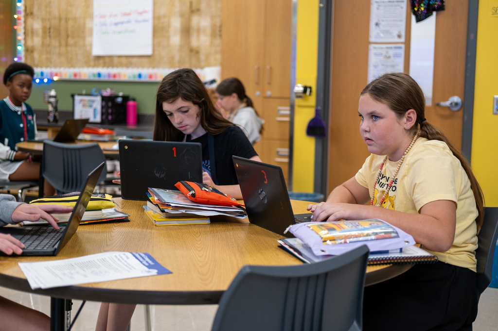 Two students type on their Chromebooks.