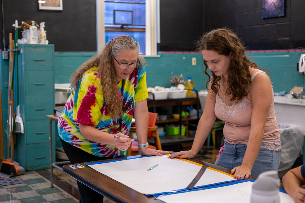 An art teacher assists a student