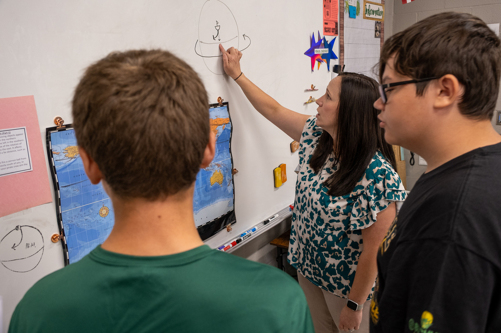 A teacher draws a picture on a whiteboard to demonstrate a point.