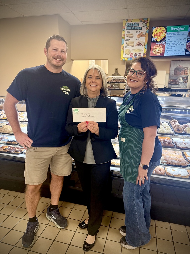 Dr. Fara Jones holds a donation alongside members from the staff at Hoeckele's Bakery and Deli.