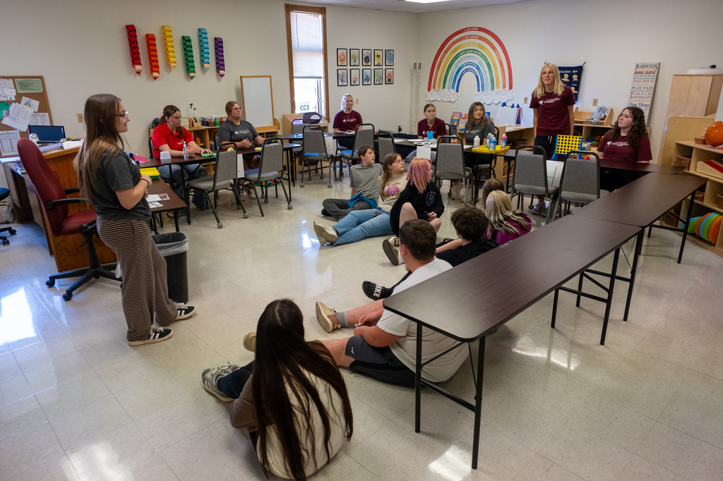 Students sit in a circle in a classroom.