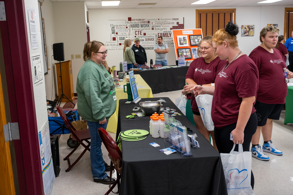 Students interact with an individual at a table during a career/college fair.