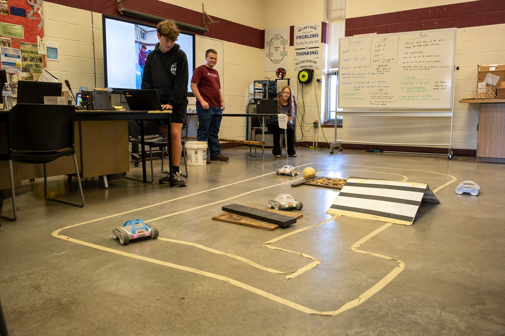 Students control remote controlled cars around a track.