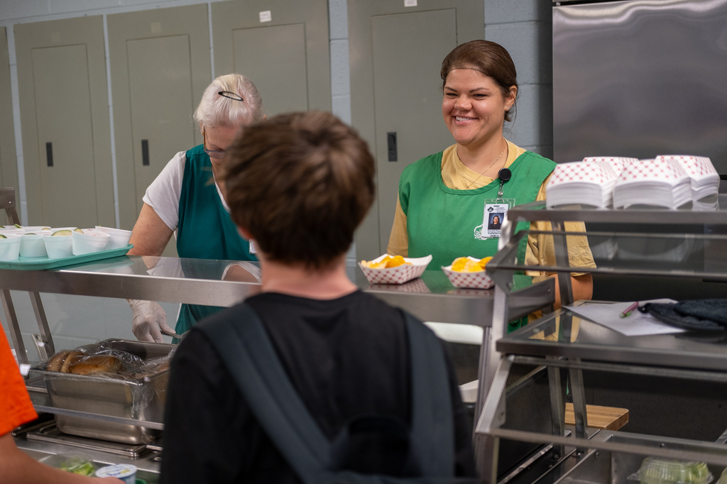 Staff serve lunch to students in a cafeteria