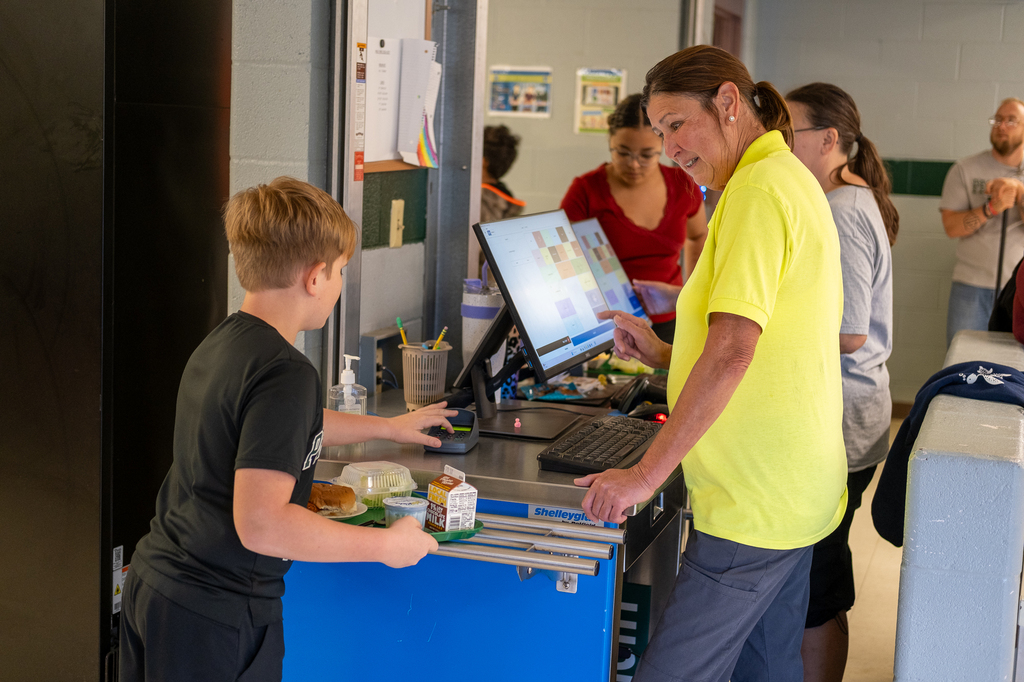 Staff serve lunch to students in a cafeteria