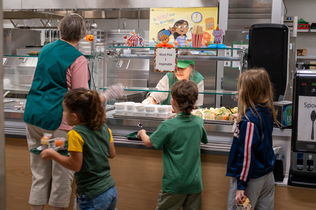Staff serve lunch to students in a cafeteria