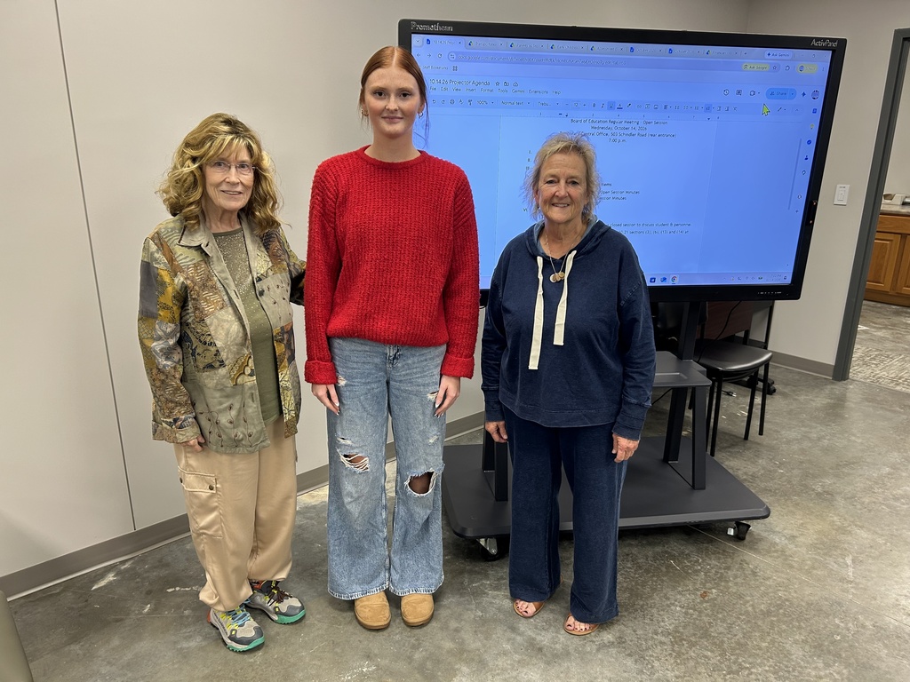 Three people stand next to a Promethean board.