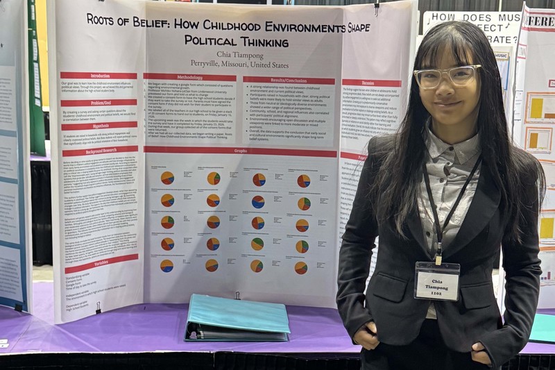Chia Tiampong stands next to her science fair project.