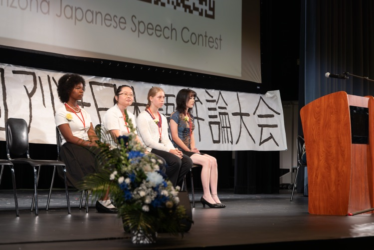 4 students sit together on a stage