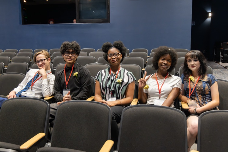 5 students pose for a photo in an auditorium seating area