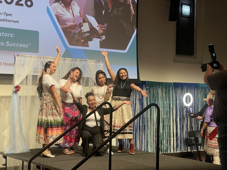 5 individuals pose for picture with arms open wide