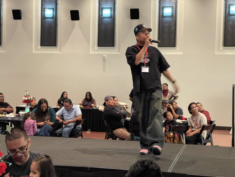 speaker on a stage with audience surrounding him