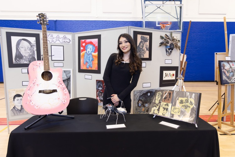 student posing with their artwork