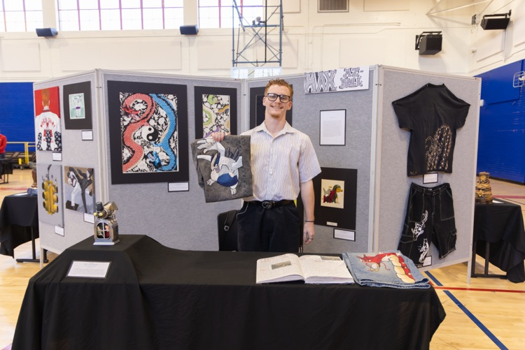 student posing with their artwork