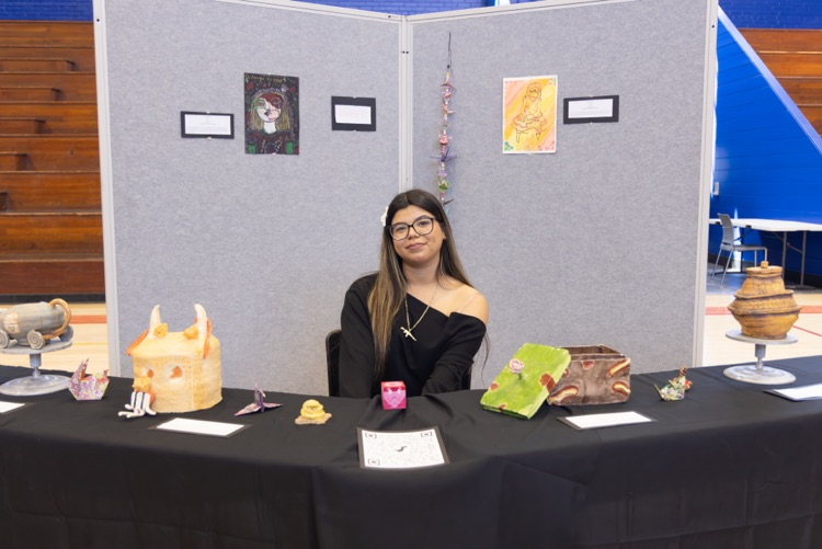 student posing with their artwork