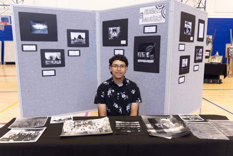 student posing with their artwork