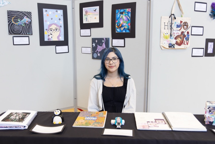 student posing with their artwork